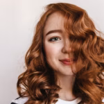 Close up shot winsome elegant girl with red hair pretty ginger female model looking with playful smile